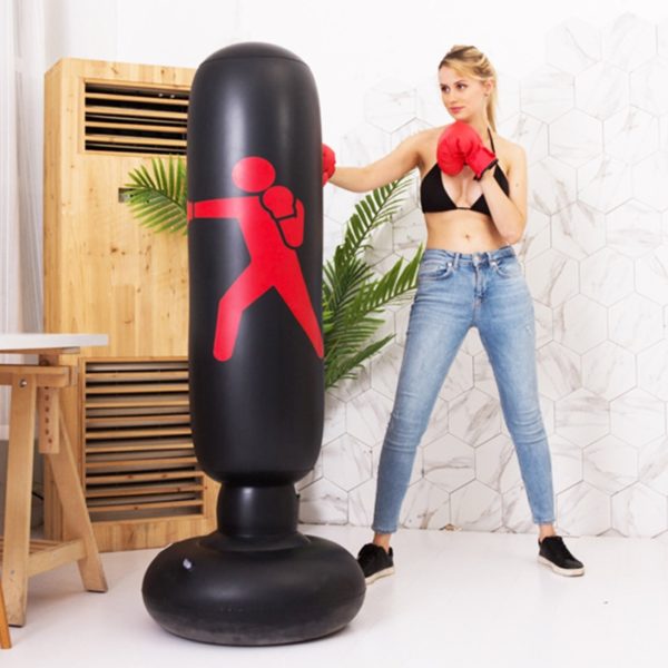 Sac de boxe sur pied gonflable pour enfants et adultes noir avec le dessin d'un bonhomme rouge, une jeune femme blonde pratique la boxe en intérieur