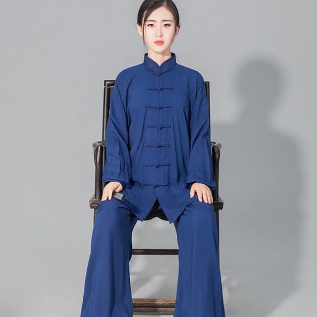 Tenue de Tai Chi en coton doux bleu portée par une jeune femme asiatique assise sur une chaise de face et les mains posées sur les genoux