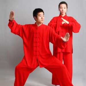 un homme et une femme portent le même ensemble de kung fu ou de tai chi de couleur rouge vif, l'homme est en position de combat, la femme se tient debout avec les mains jointes