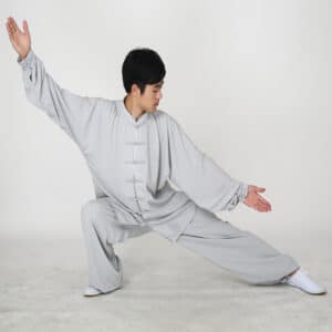 jeune homme en position de combat et porte une uniforme traditionnel de kung fu gris clair