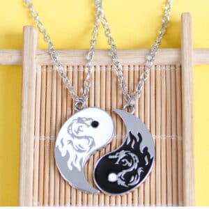 collier de couple de tai chi , ying et yang, représentant un dragon sur chaque partie, posés sur un support en bois fin