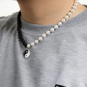 jeune homme dont on n evoit que le cou, porte un collier de perles noires d'un côté et blanches de l'autre, et un pendentif ying yang