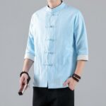 jeune homme dont on ne voit pas le visage, porte une chemise traditionnelle chinoise bleue pour homme entre-ouverte, avec les manches retroussées