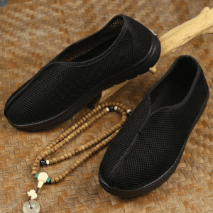 paire de chaussure souples pour les arts martiaux et le kungfu, posé au sol avec, entre les deux chaussures, un collier de prière bouddhiste