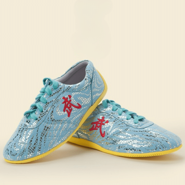 Paire de chaussures de Tai chi bleues, avec la semelle jaune et un signe chinois brodé sur le côté. Présentées sur fond jaune pâle, une chaussure de trois-quarts vers la droite, et l'autre calé le talon sur la première chaussure et la pointe sur le sol, de trois-quarts vers la gauche.