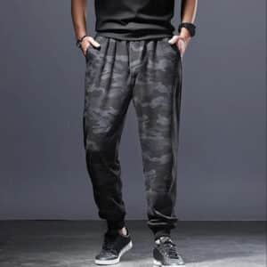 Pantalon Savate Gris de Style Camouflage pour Homme sur un homme avec des baskets et un t shirt noir sur fond gris